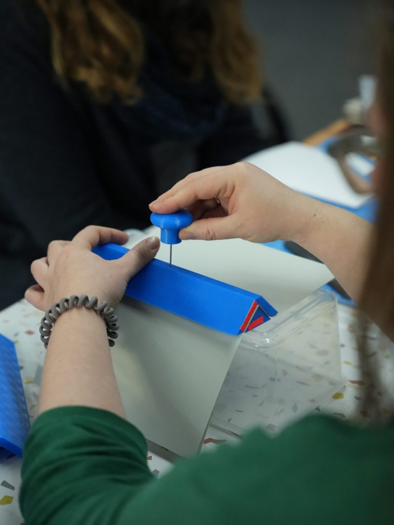 Foto zweier Hände beim Buchbinden mit 3D-gedruckten Werkzeugen