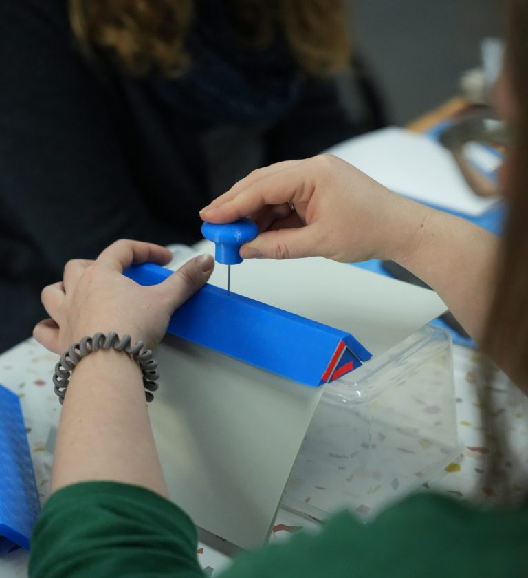 Foto zweier Hände beim Buchbinden mit 3D-gedruckten Werkzeugen